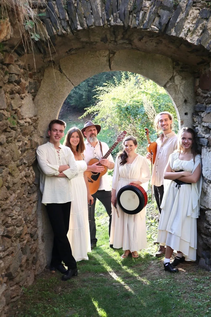 Die Band mit Gitarre, Bodhrán und Fiddle in einem alten Steintorbogen